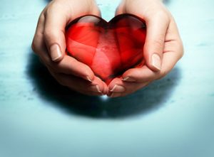 Holding red glass heart in hands